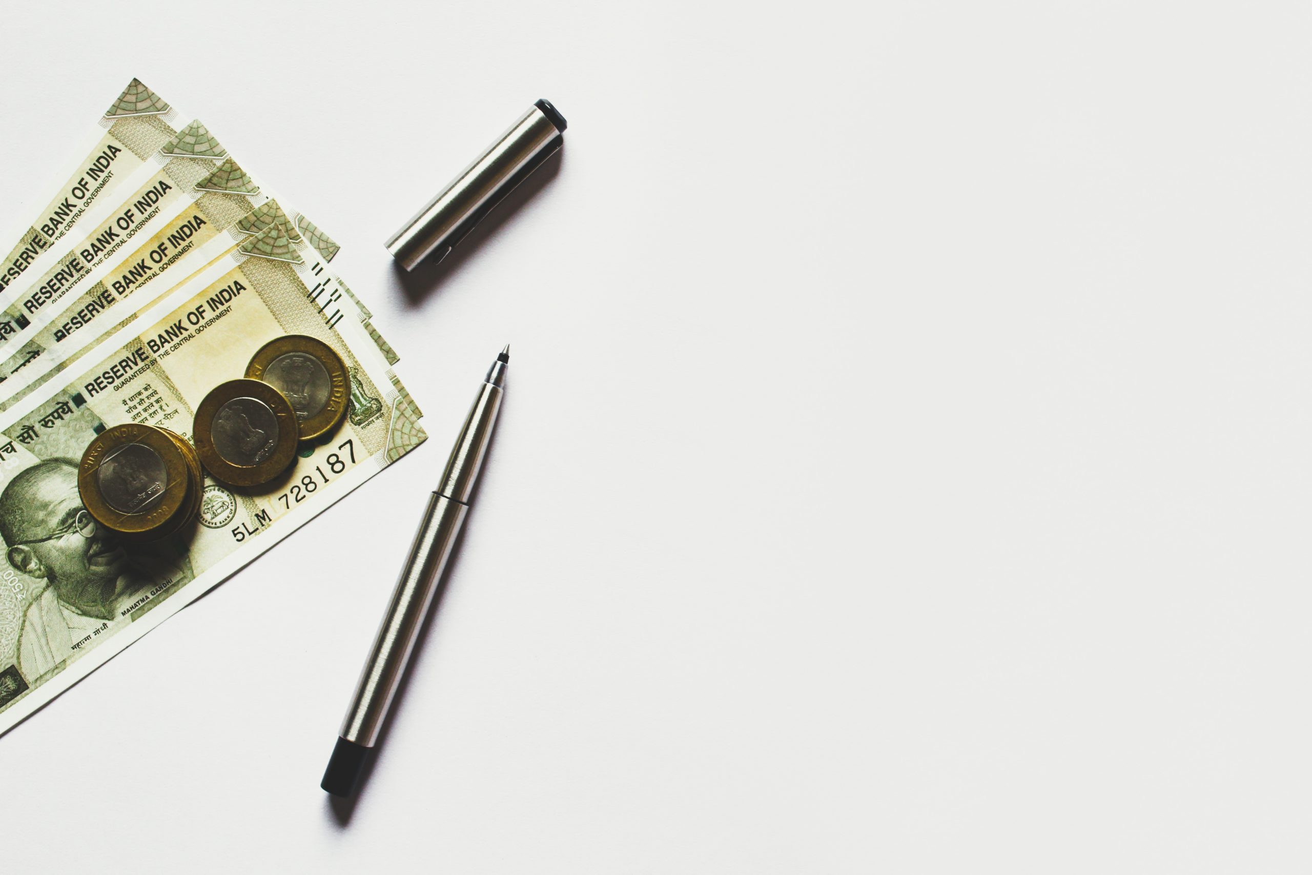 Briefgeld, muntgeld en een pen op een witte achtergrond